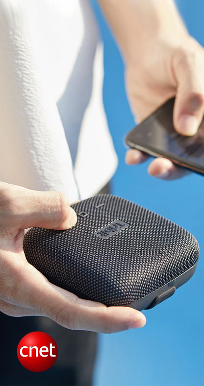 Person holding a black portable speaker with a blue background