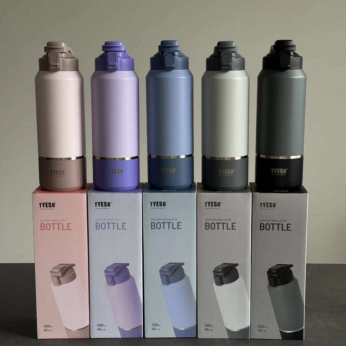 Five Yeso water bottles in different colors with matching boxes on a neutral background