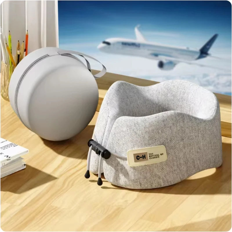 Gray travel pillow on a wooden surface with an airplane in the background