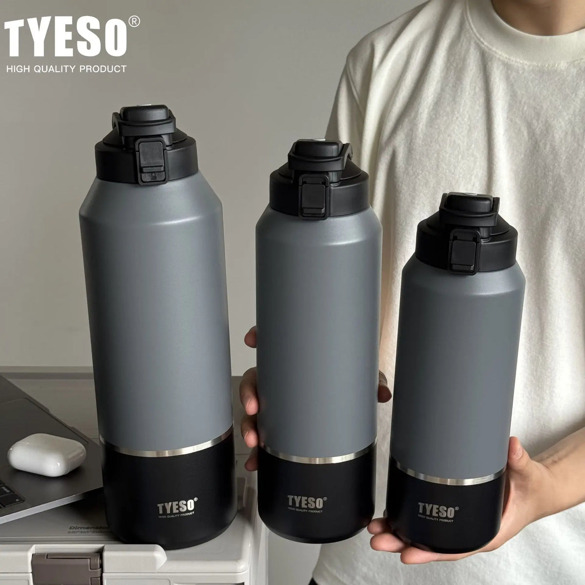 Three gray TYESO water bottles with black caps held by a person.