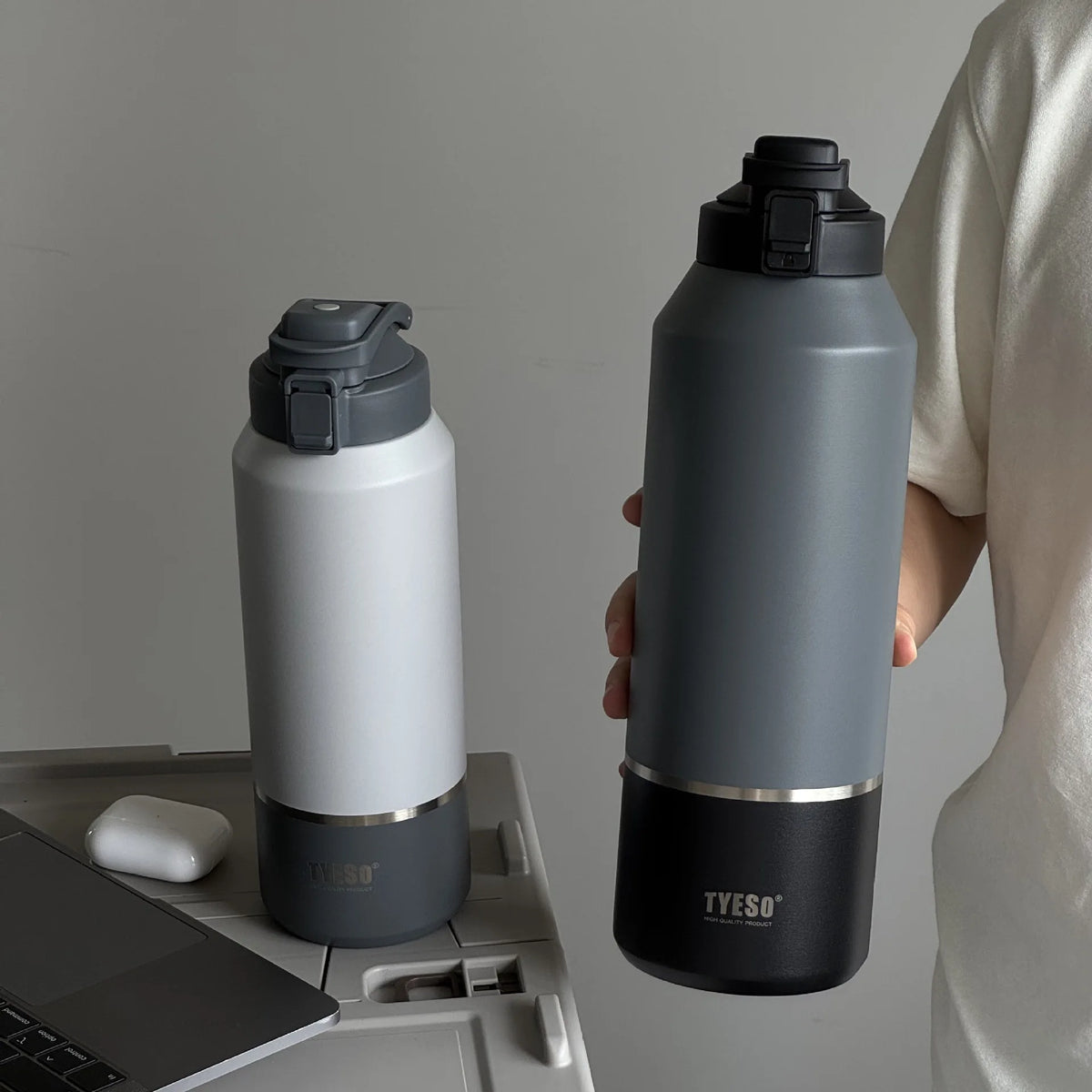 Two water bottles, one black and one white with gray accents, on a desk.