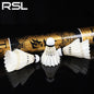 Three white badminton shuttlecocks in front of a gold and black RSL badminton racket on a black background.