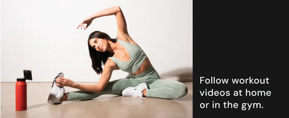 Woman stretching on the floor with a water bottle and phone beside her, text promoting workout videos.