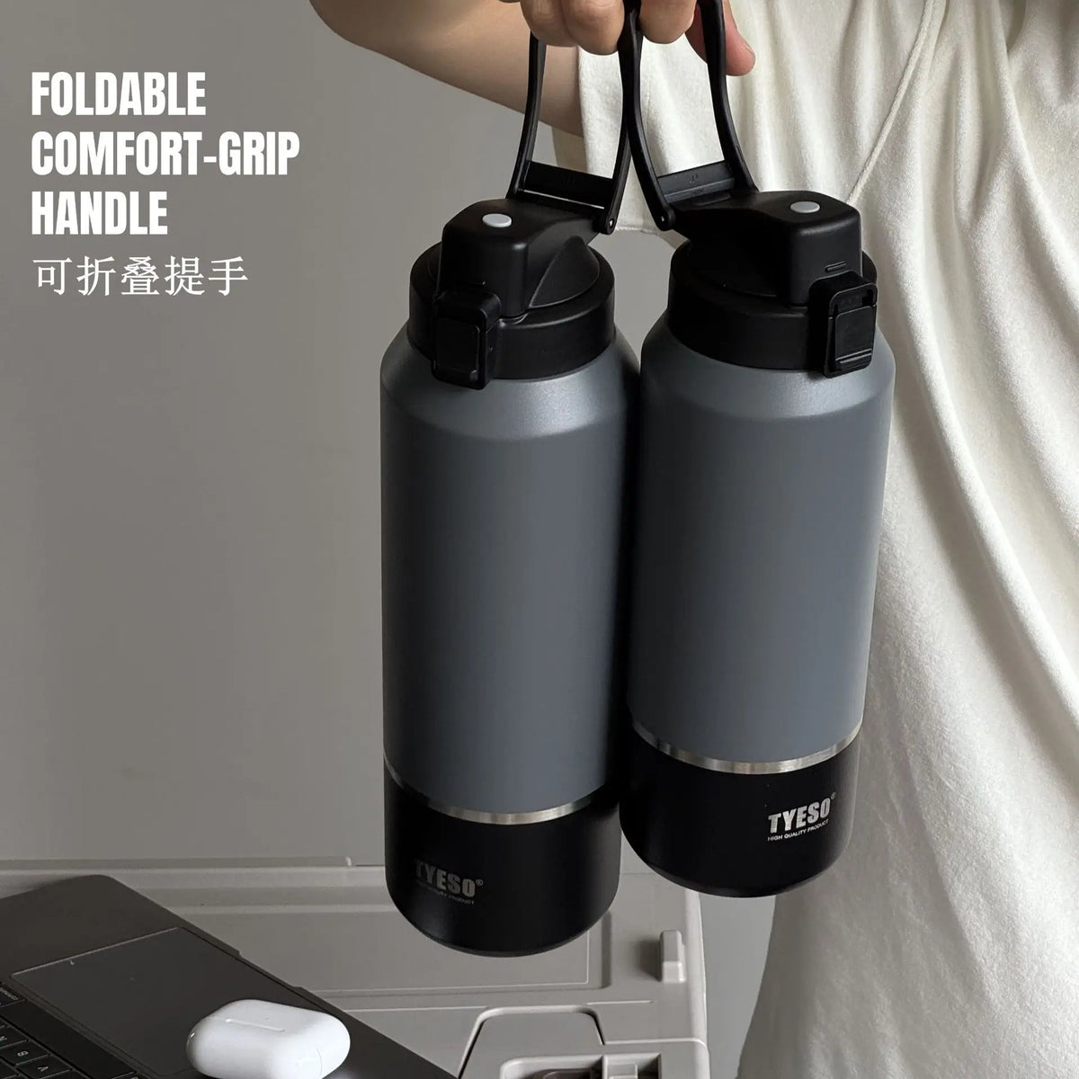 Two gray water bottles with black lids and handles held by a person, with 'TYESO' branding.