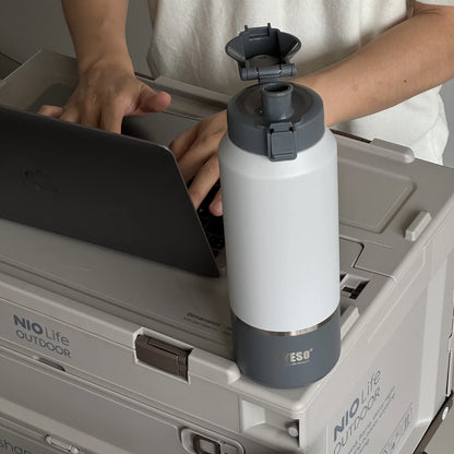 Person holding a white and gray water bottle over a NIO Life Outdoor cooler.