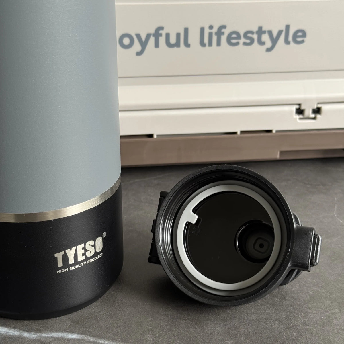 TYESO mug with a lid on a surface, with 'oyful lifestyle' branding in the background.