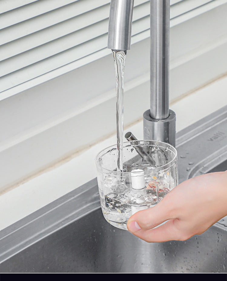 Clear glass with water being poured from a faucet into it, with a hand holding the glass.